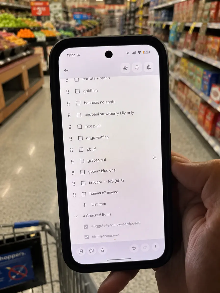 Hand holding phone in grocery store showing a chaotic shopping notes list
